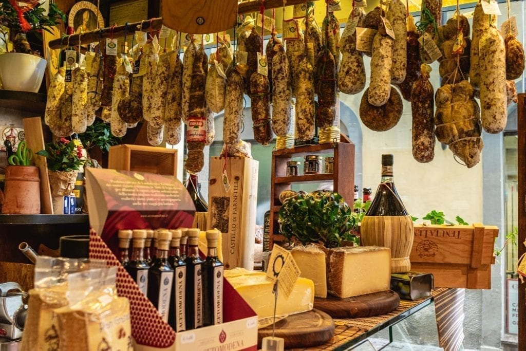 sausages hanging in a small shop in florence, how to save for a trip includes eating at home more