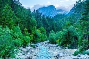 Soca River in Slovenia with trees on either side and a mountain visible in the background, as seen during a Slovenia road trip