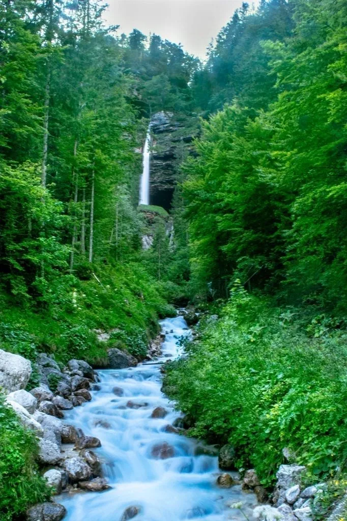 Pericnik Falls in Slovenia with flowing Soca River in the foreground