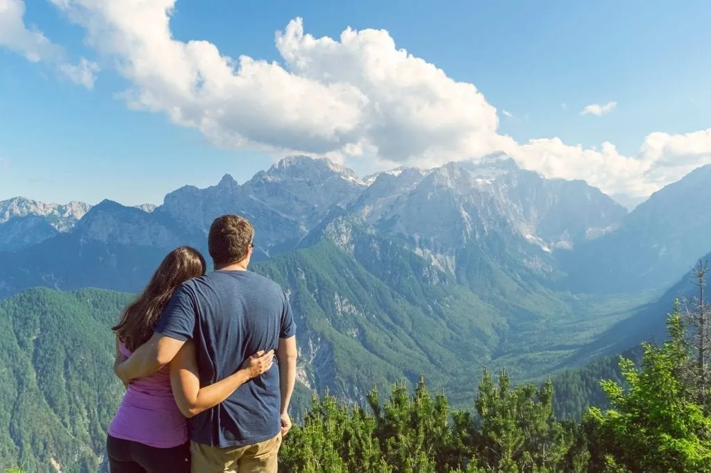 Kate Storm and Jeremy Storm looking away from the camera and overlooking the Vrata Valley in Slovenia, as seen during a Slovenia road trip