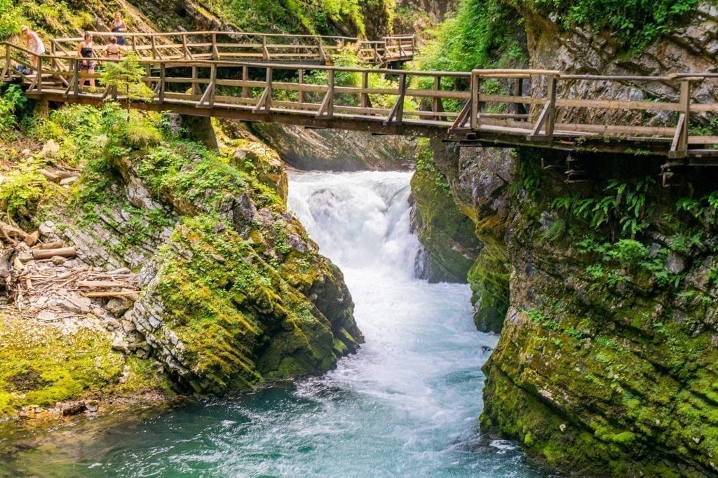 Photo of the Vintgar Gorge waterfall with a wooden boardwalks across it. Vintgar Gorge is one of the best day trips from Ljubljana Slovenia