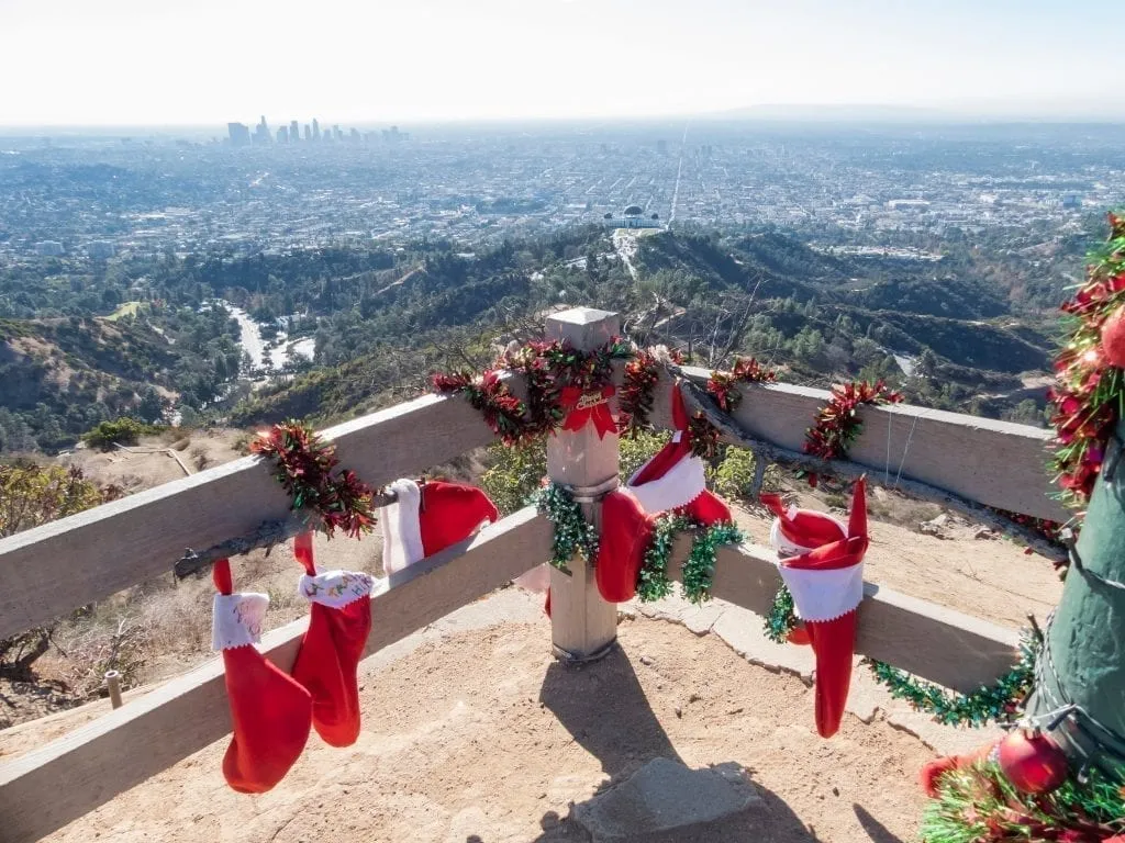 View of LA skyline from Griffith Park with stockings and holiday decor in the foreground--you can expect decor like this when visitin LA on a USA Christmas trip