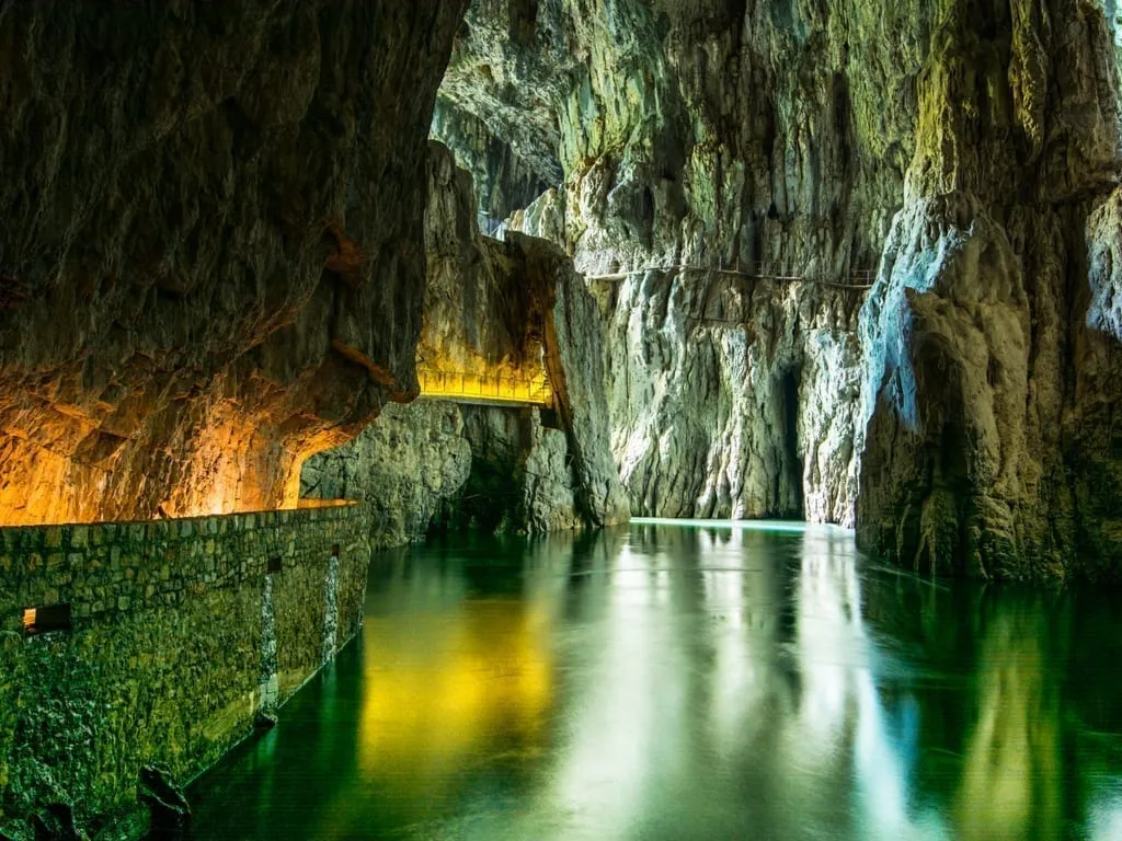 Underground river in Skocjan Cave in Slovenia, with a lit walkway visible on the left side of the photo