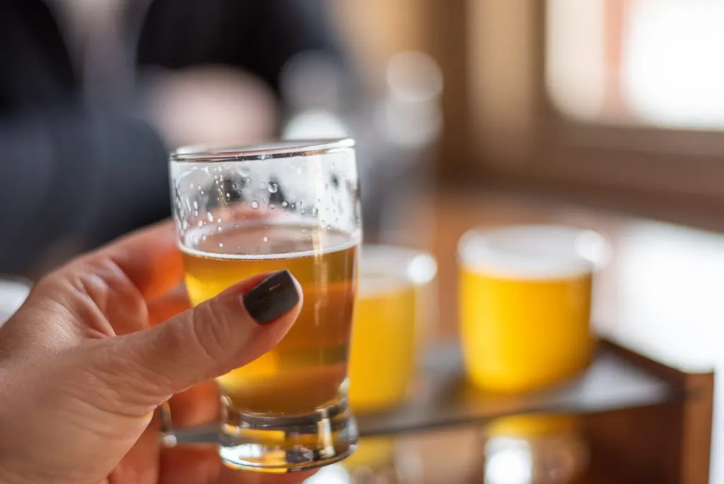 woman holding a glass of beer from a flight at a milwaukee brewery