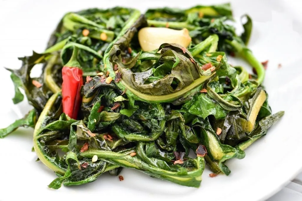 Cicoria Ripassata on a white plate, one of the best things to eat in Rome Italy