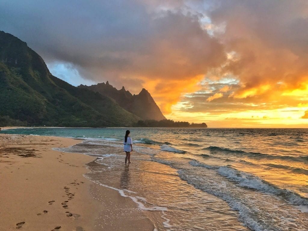Tunnels Beach on Kauai at sunset, a woman is visible in the background
