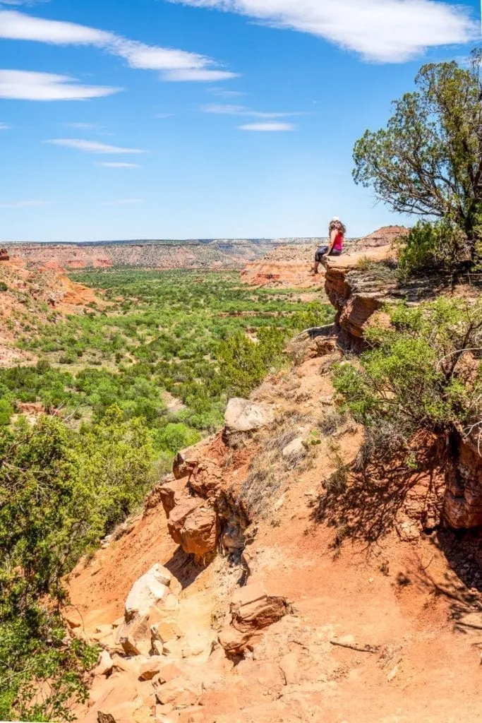 Kate Storm sitting on a ledge on the Palo Duro Canyon Lighthouse trail overlooking the canyon