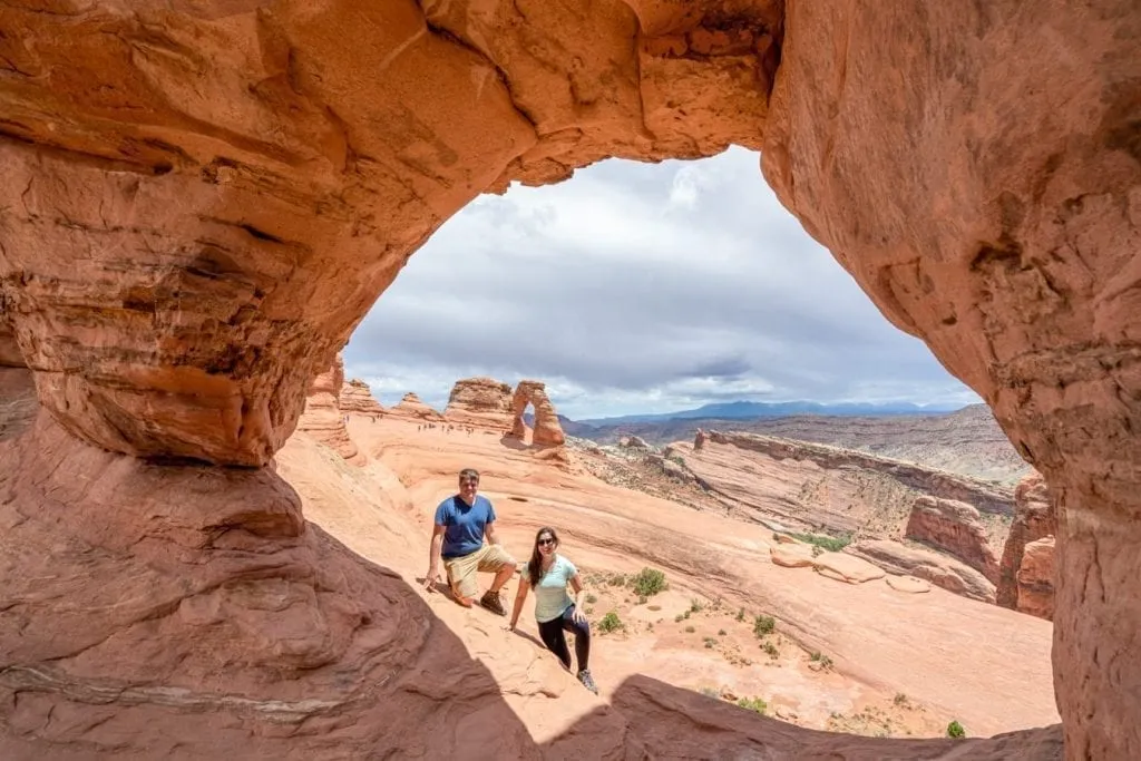 Kate Storm and Jeremy Storm sitting inside Twisted Doughnut Arch on the Delicate Arch trail