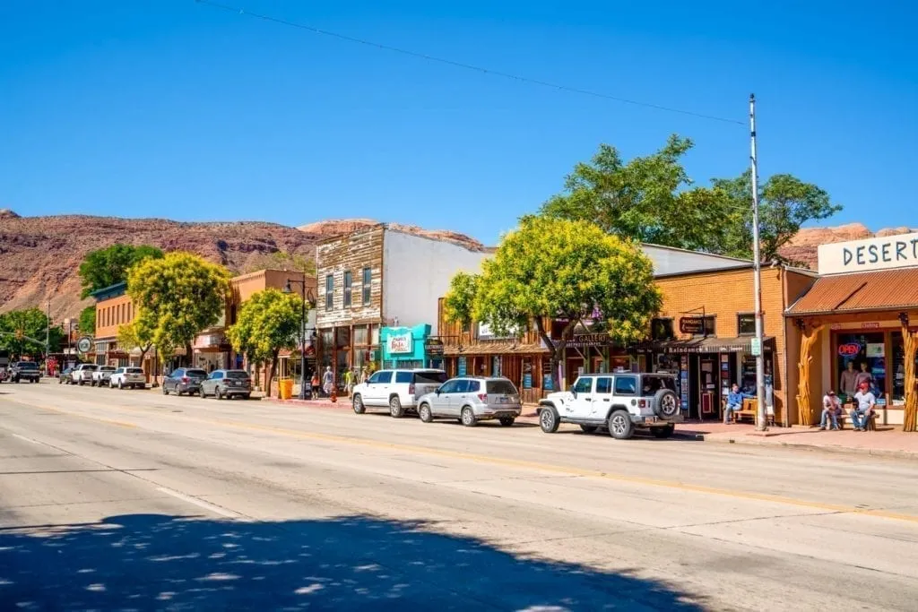 Street in downtown Moab Utah with cars parked in front of colorful buildings