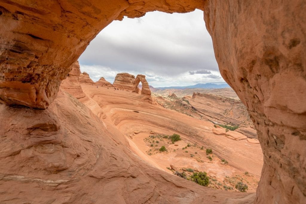 view of delicate arch in arches np on a cloudy day through twisted doughnut arch