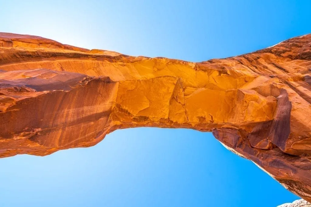 sandstone arch framed by blue sky in arches np utah