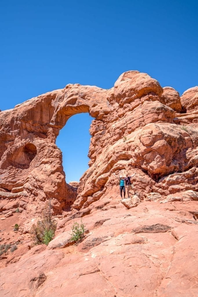 Kate Storm and Jeremy Storm standing in front of Turret Arch when hiking in Arches National Park itinerary