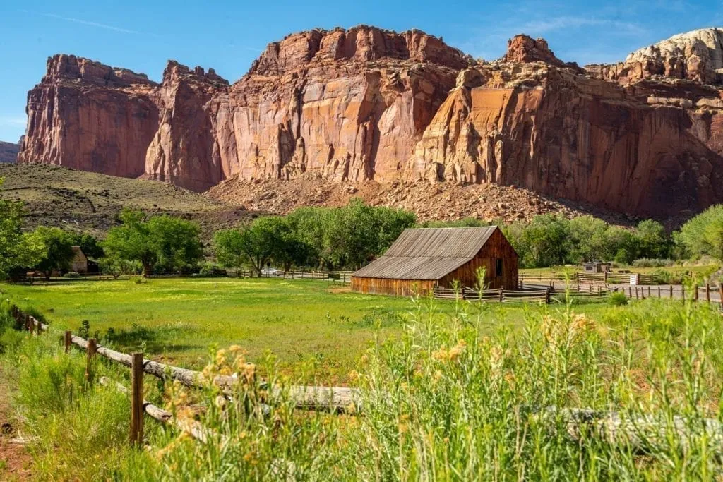 Fruita Historic District in Capitol Reef NP with a fence in the foreground and a rock formation in the background