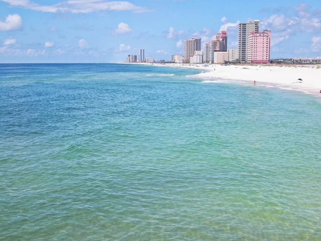 Orange Beach Alabama as seen from the water, with small grouping of skyscrapers in the background. Orange Beach is one of the prettiest white sand beaches in the USA