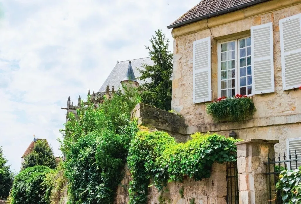 Classic French building with shutters in Senlis France with greenery to the left