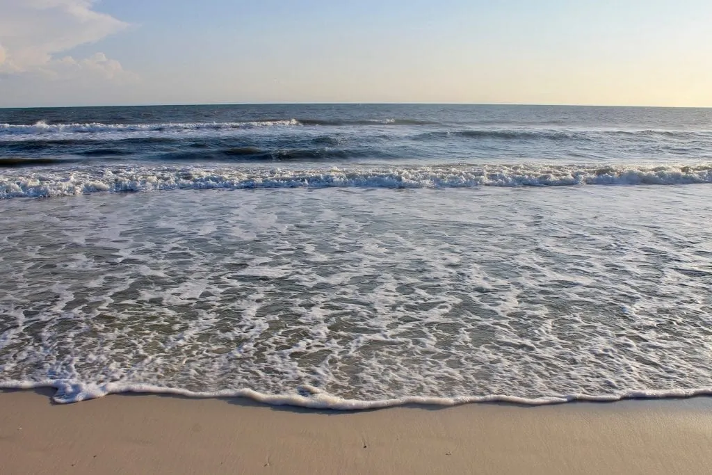 Cape San Blas Beach in Florida, with gold sand visible in the foreground and layers of waves approaching the shore in the background.