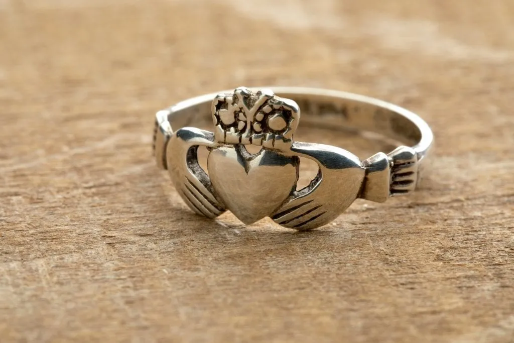 Irish Claddagh ring sitting on a wood surface. When deciding what to buy in Ireland, consider this traditional ring.