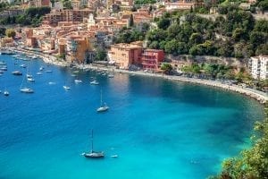 Villefranche-sur-Mer as seen from across the water with sailboats and water in the foreground. Villefranche-sur-Mer is one of the prettiest villages in France