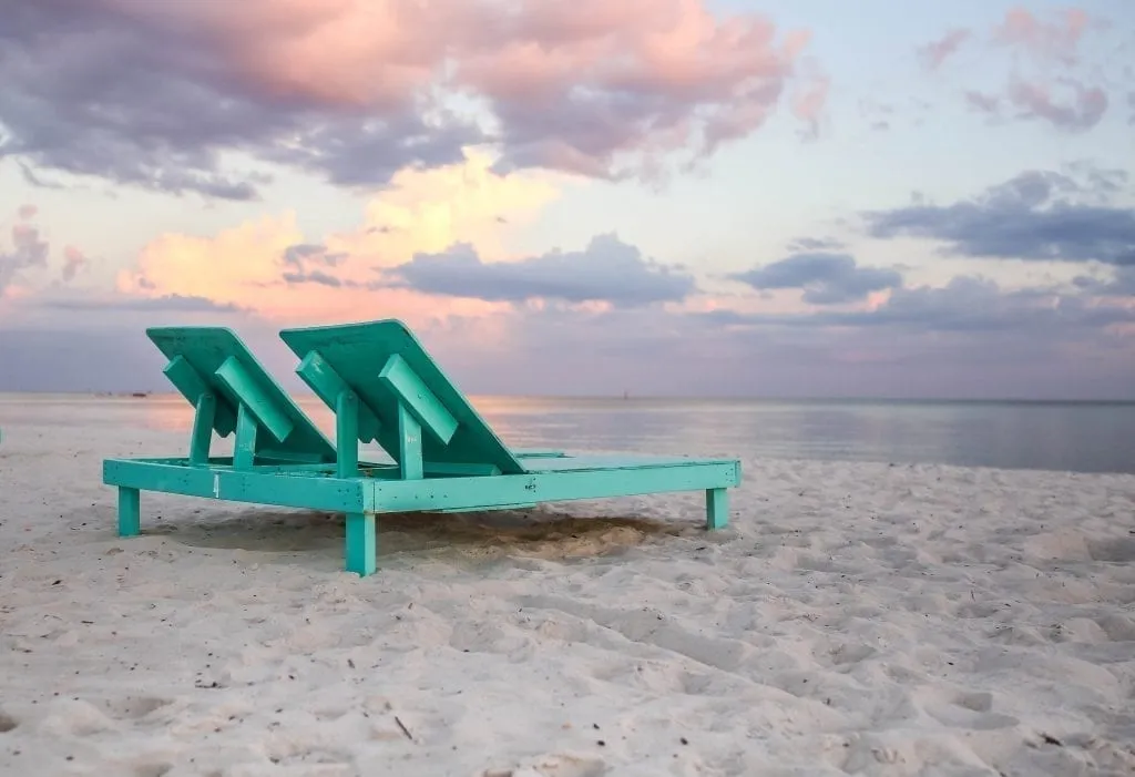 Wooden, teel beach chairs set out on Biloxi Beach at sunset, one of the best white sand beaches in USA