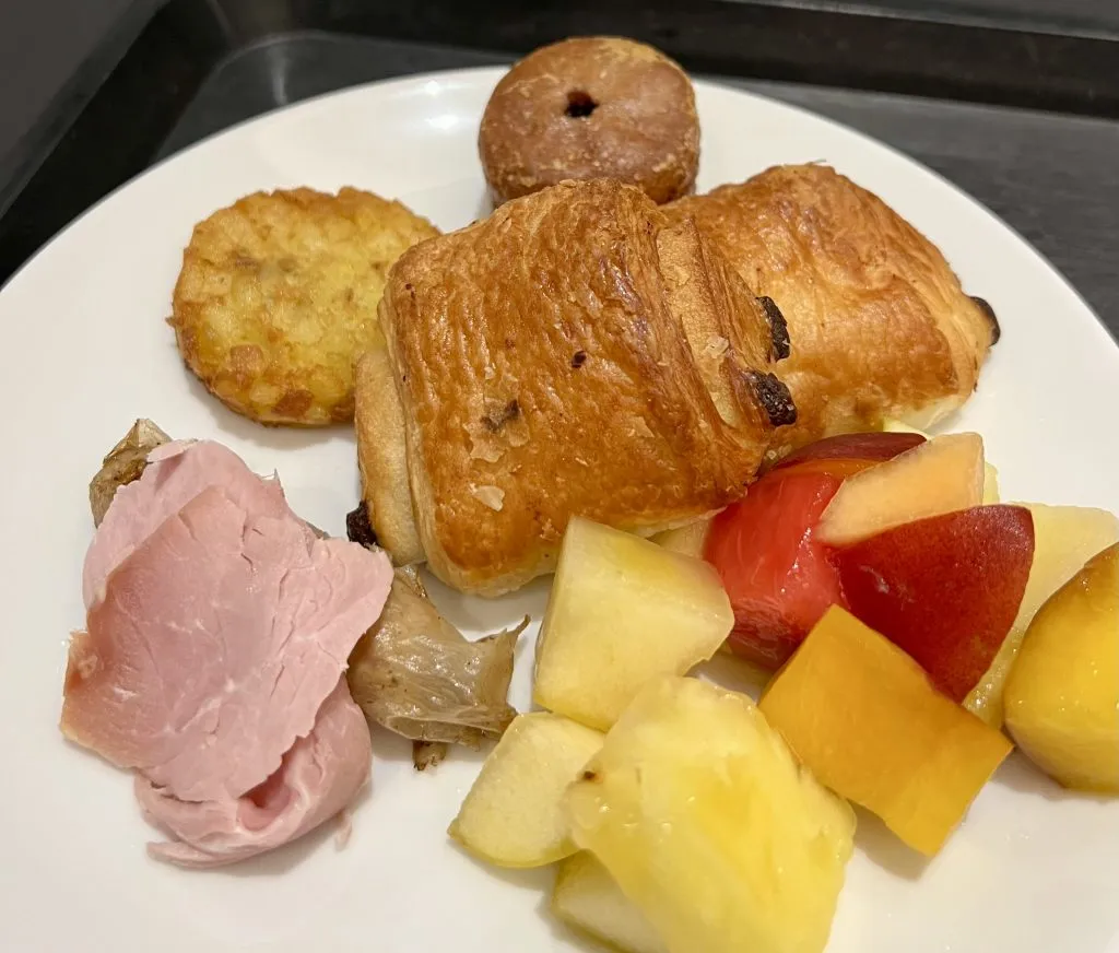 pain au chocolat with side of fruit and meat at french breakfast hotel buffet