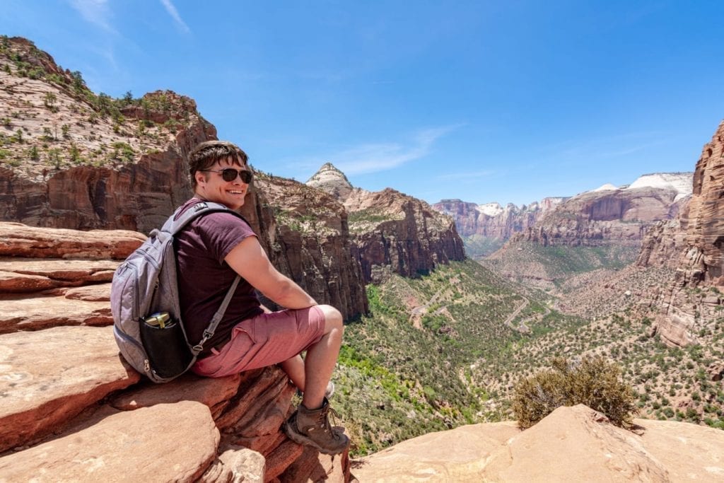 Jeremy Storm relaxing at the end of the Zion Canyon Overlook hike with the view in the background