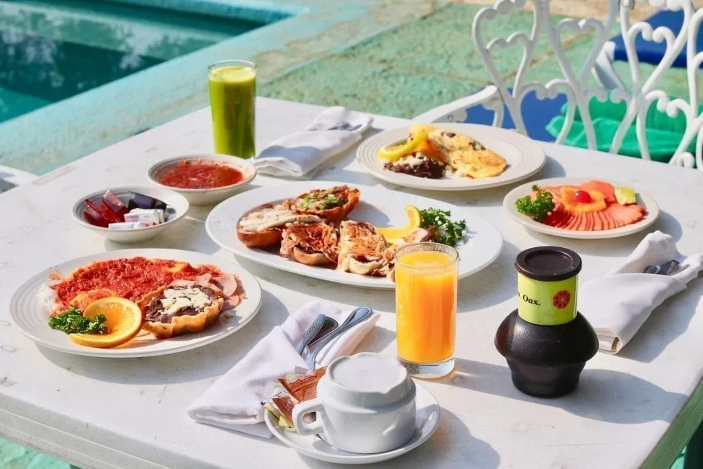 Mexican breakfast spread at a restaurant on a white tablecloth with a fruit juice at each place setting