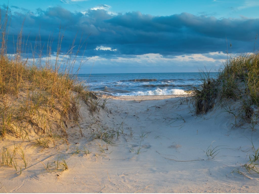 Sand dunes at Fort Macon North Carolina with the ocean visible distance near sunset
