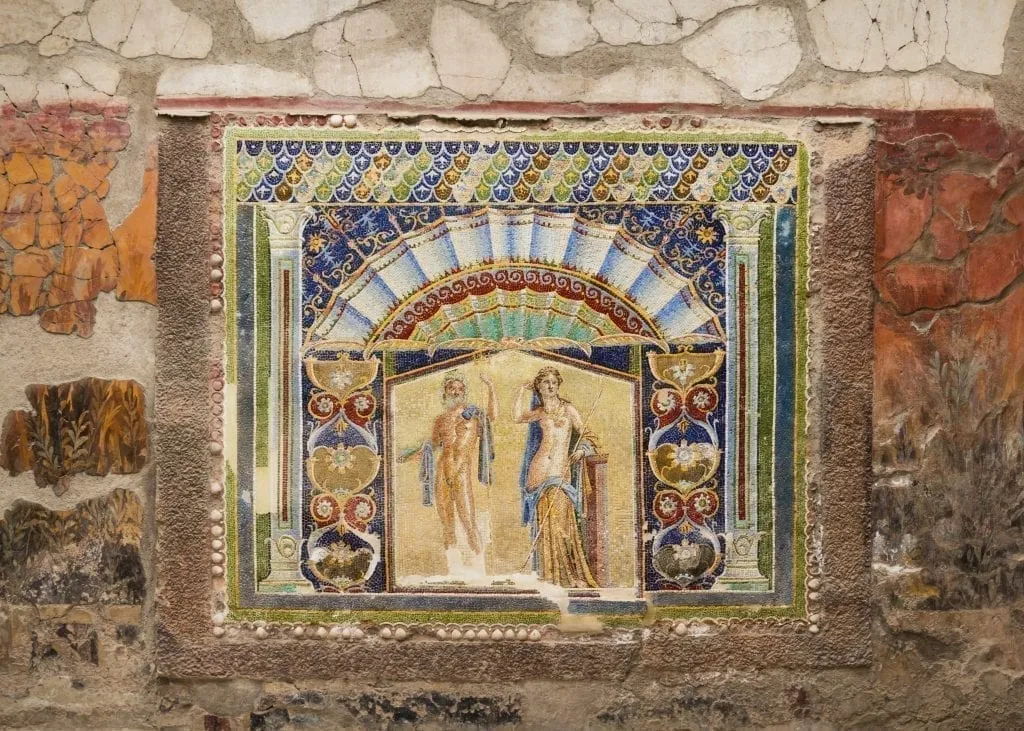 Fresco of two people on a wall inside a wall in Herculaneum--when deciding whether to visit Herculaneum or Pompeii, know that Herculaneum has better frescoes