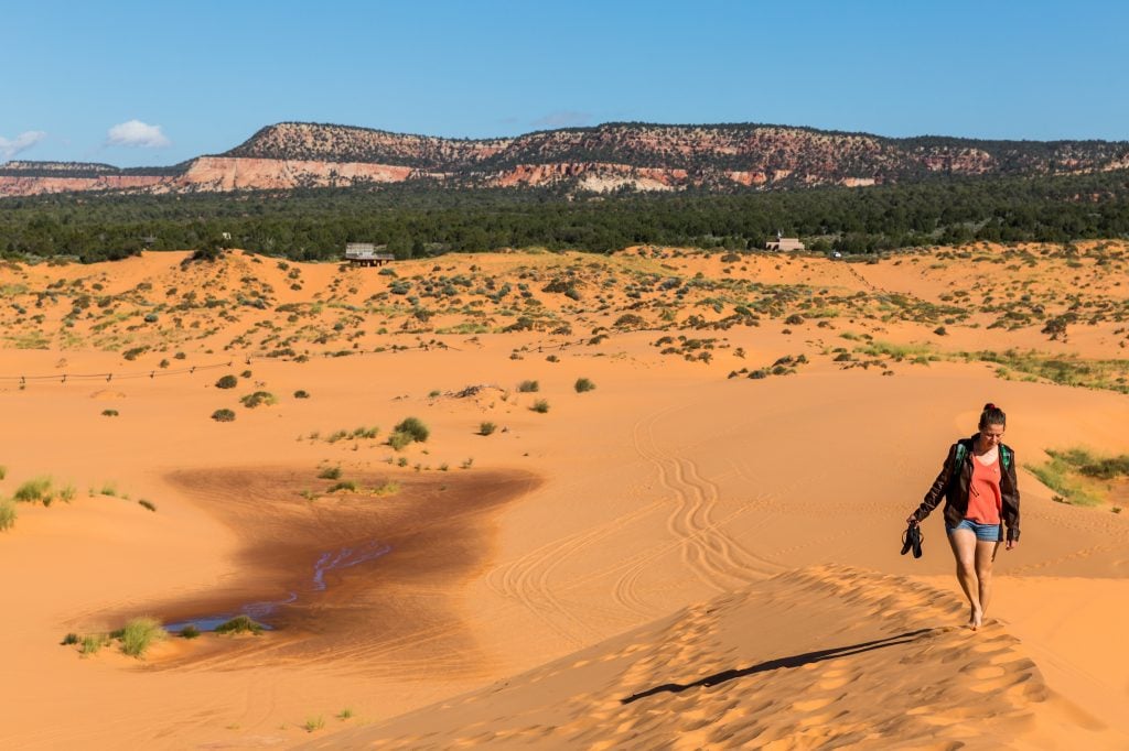 woman climbing a sand dune in coral sand dunes state park when visiting utah travel