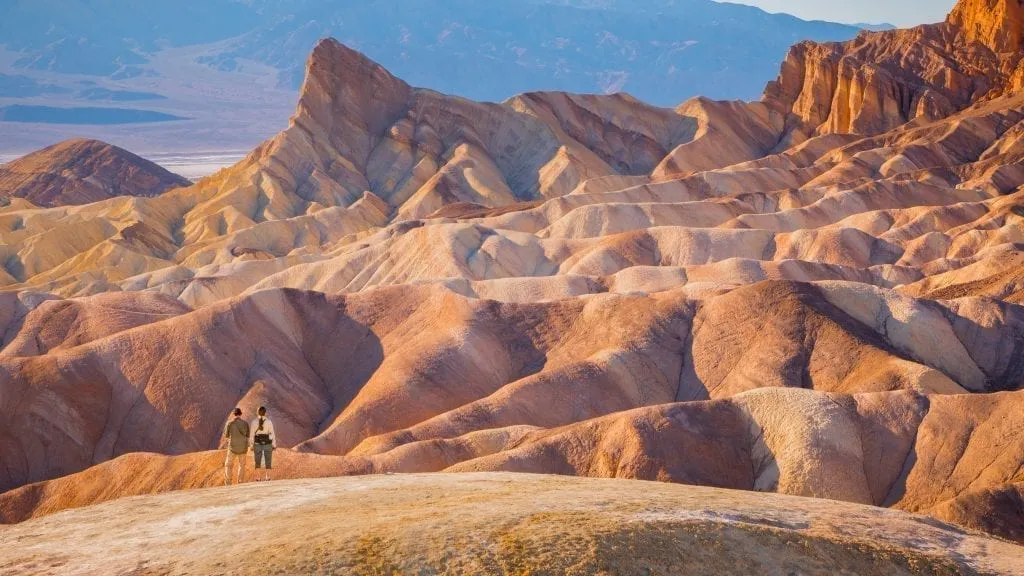 Martian landscape of Death Valley NP with 2 small humans in the bottom left corner. Death Valley belongs on any bucket list for the united states