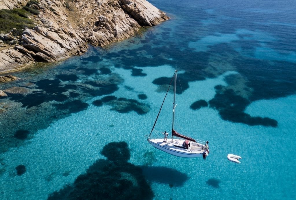 White sailboat in the clear blue sea surrounding Sardinia as seen from above--Sardinia is one of the most romantic places in Italy