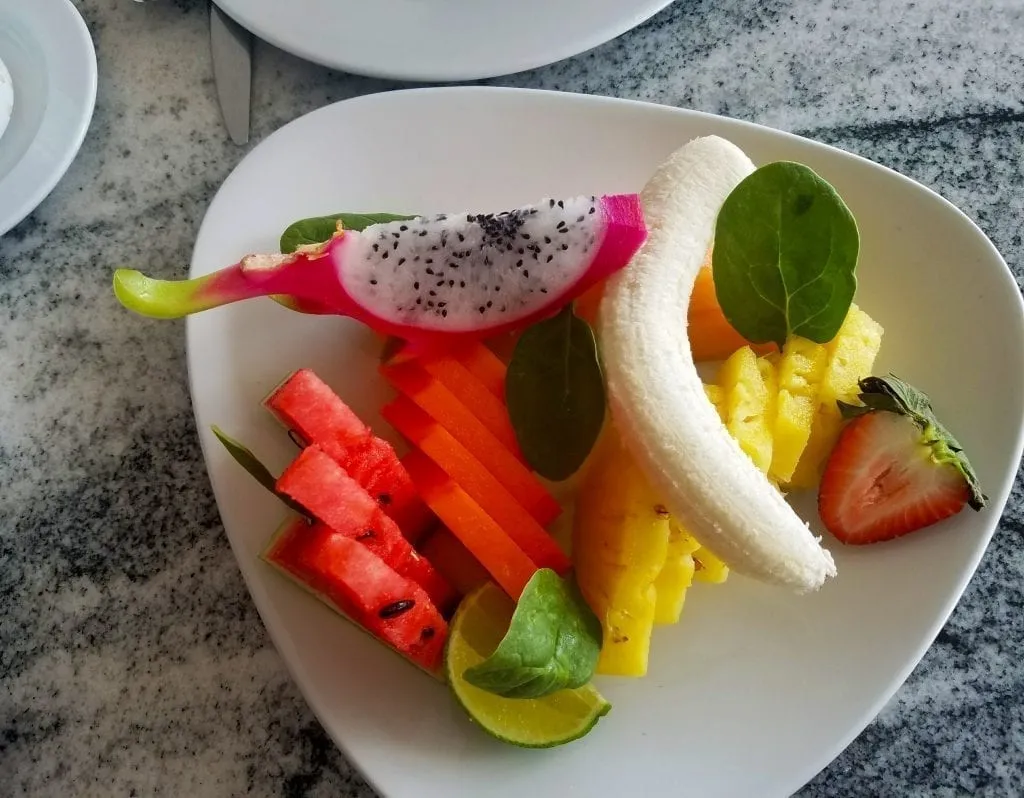 Triangle white plate stacked with tropical fruit including dragonfruit and a banana at a breakfast in Mexico