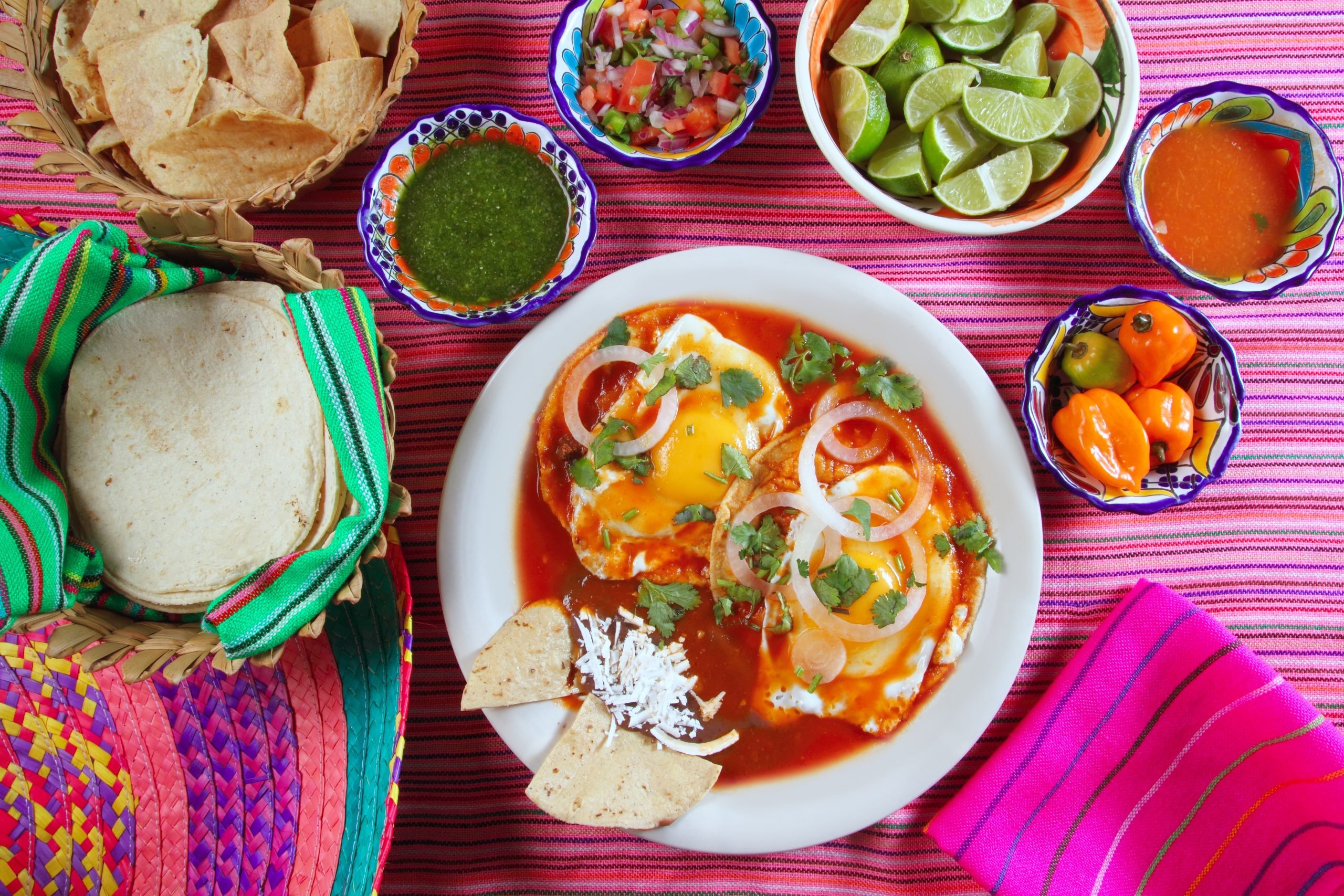 Huevos agorhados as seen from above on a pink tablecloth surrounded by sides during a breakfast in Mexico