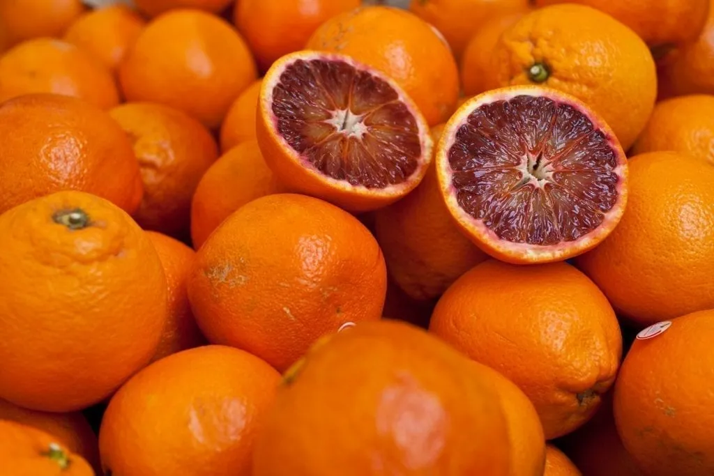 Stack of blood oranges with one in half cut on top. Oranges are a popular Sicily food