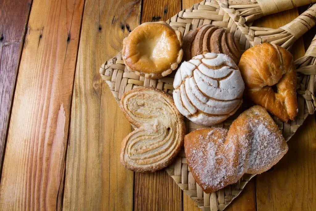 Tray of pan dulce options on a wooden table. Pan dulce is a popular food in Mexico