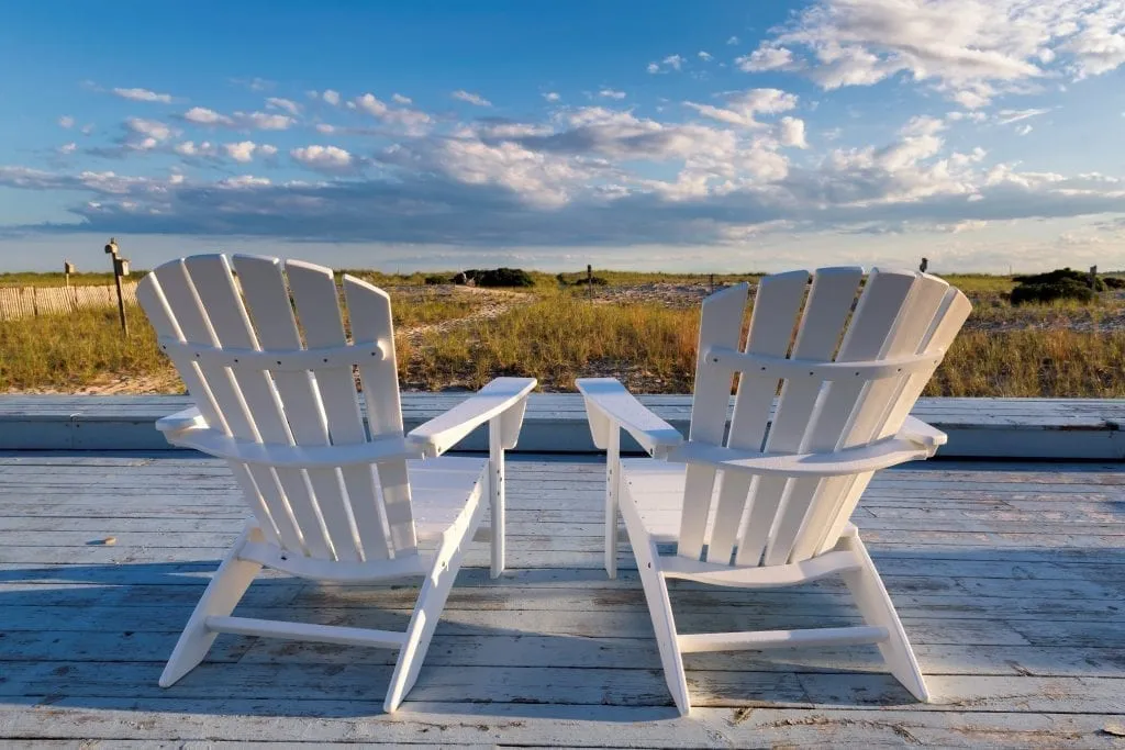 Two white chairs set up overlooking a blue sky on a New England coast