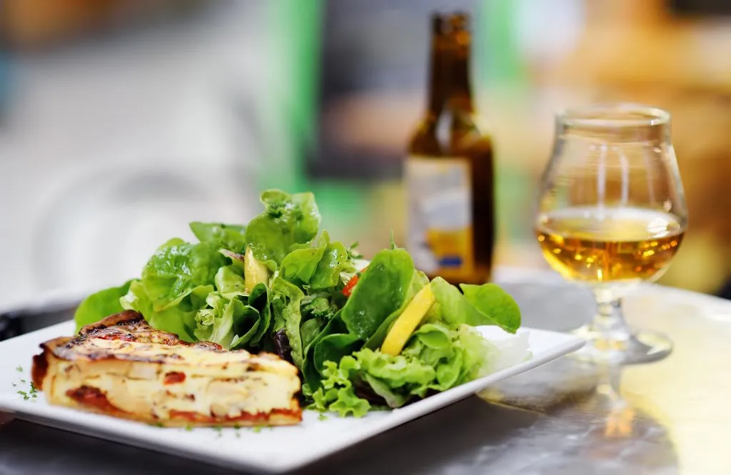 lunch on an outdoor terrace in france with a salad and cider