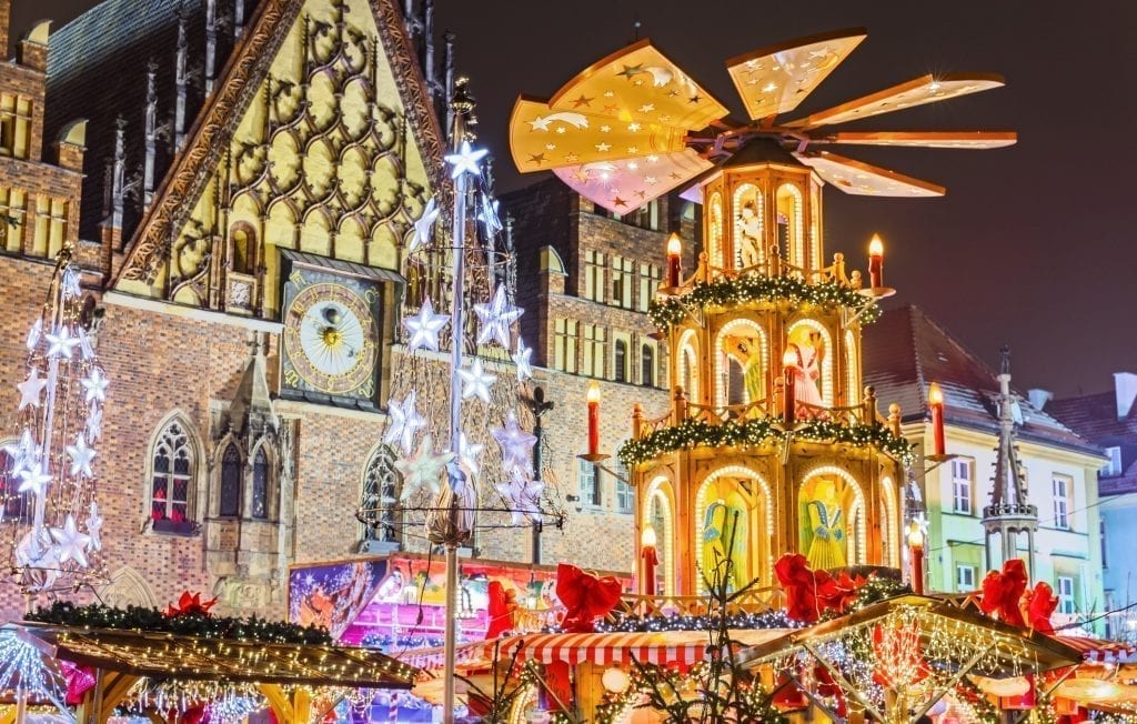 close up of the wroclaw christmas market at night with decor in the foreground and market square buildings in the background