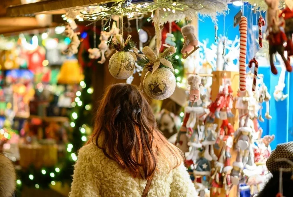 Brunette woman shopping at a booth selling ornaments at a europe christmas market