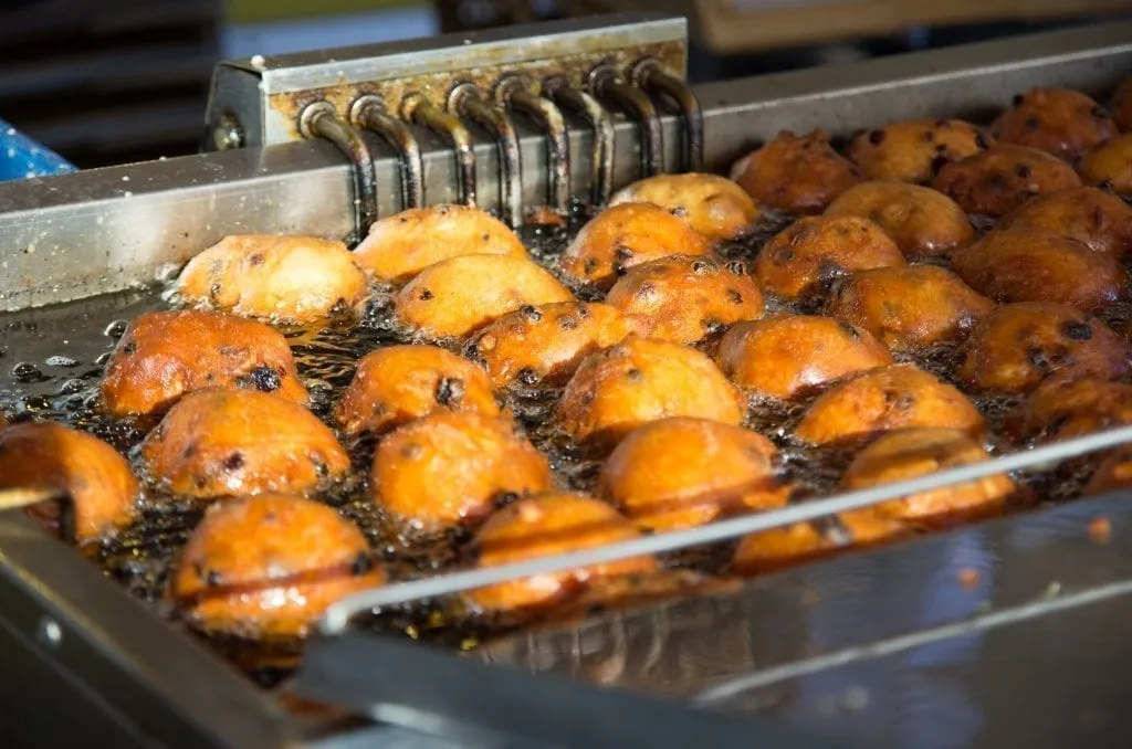 oliebollen in a vat of oil being fried. oliebollen are a must-try snack in amsterdam in winter