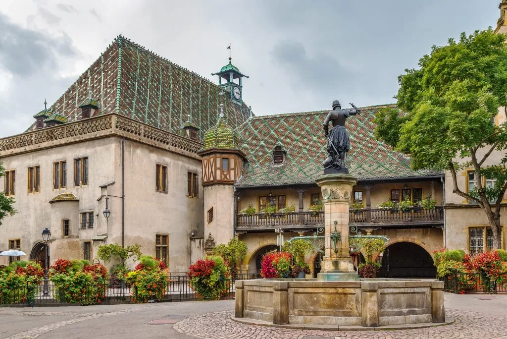 front facade of old customs house of colmar france with fountain in front