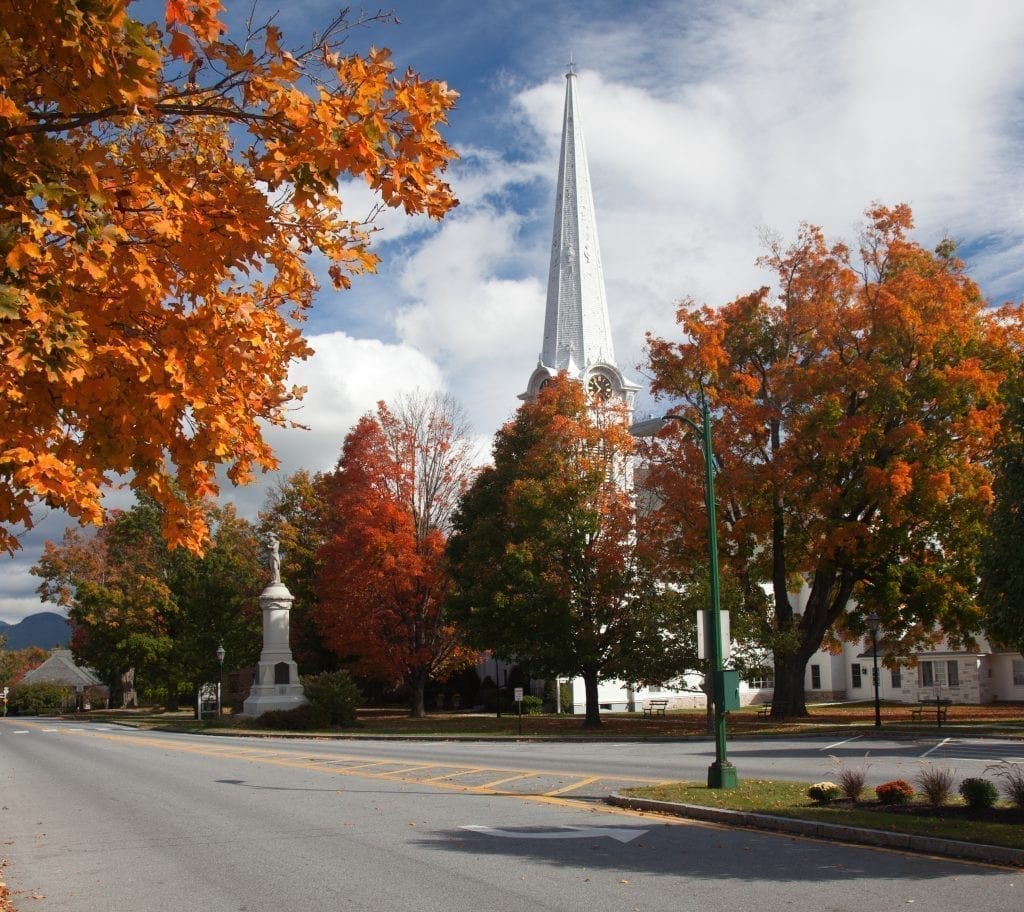 Fall foliage along a small street in Manchester Vermonth with a white church visible in the background