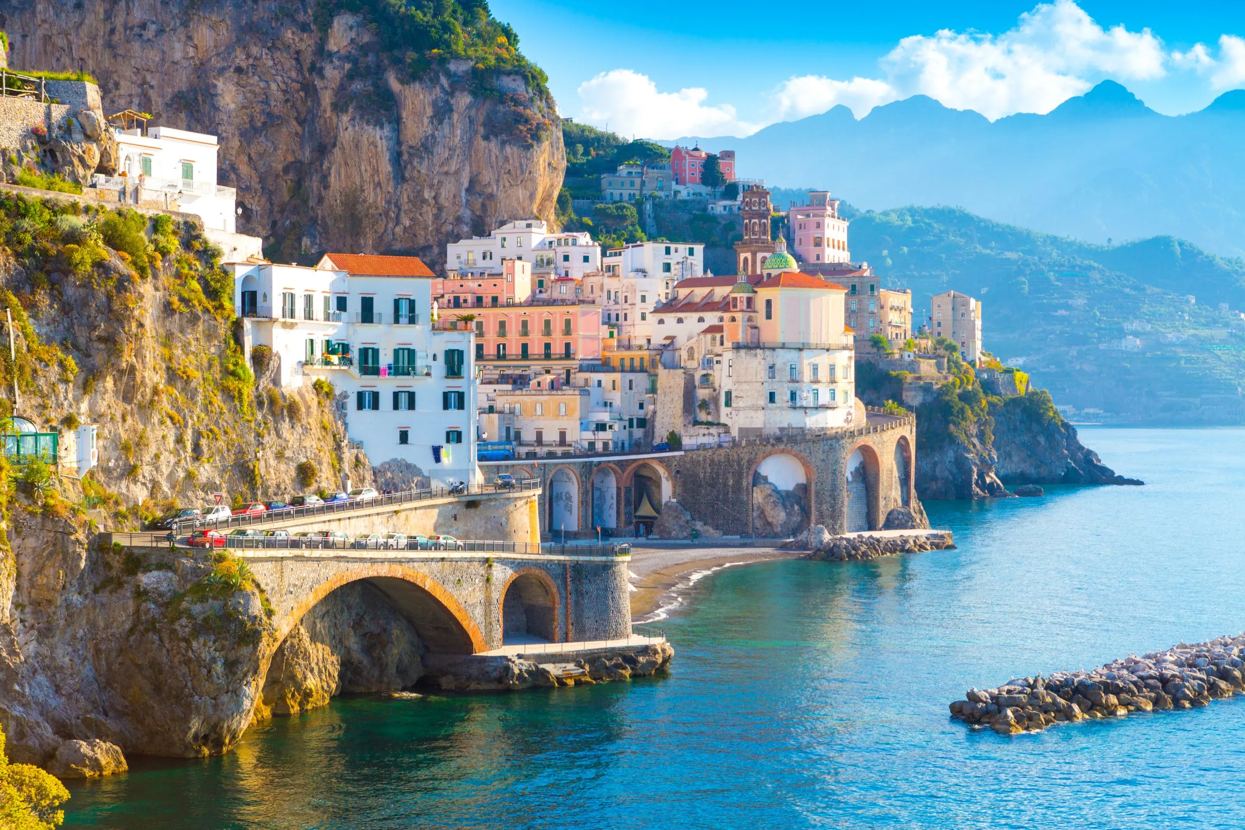 View of the Amalfi Coast with the sea to the right and a village on the left. The beautiful Amalfi Coast is one of the best places to visit in Italy.