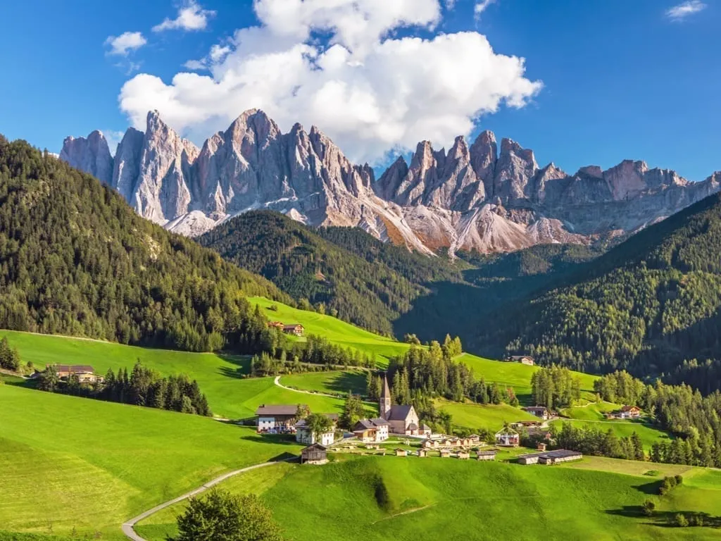 View of the Italian Dolomites on a clear day with a village visible below it.