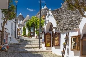 Small street in Alberobello surrounded by white trulli. this village in puglia is one of the best small towns in italy Italy lined with trulli, one of the best travel destinations in Italy
