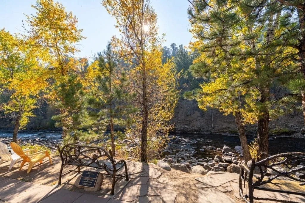 iron benches set along the riverwalk with fall foliage in the trees