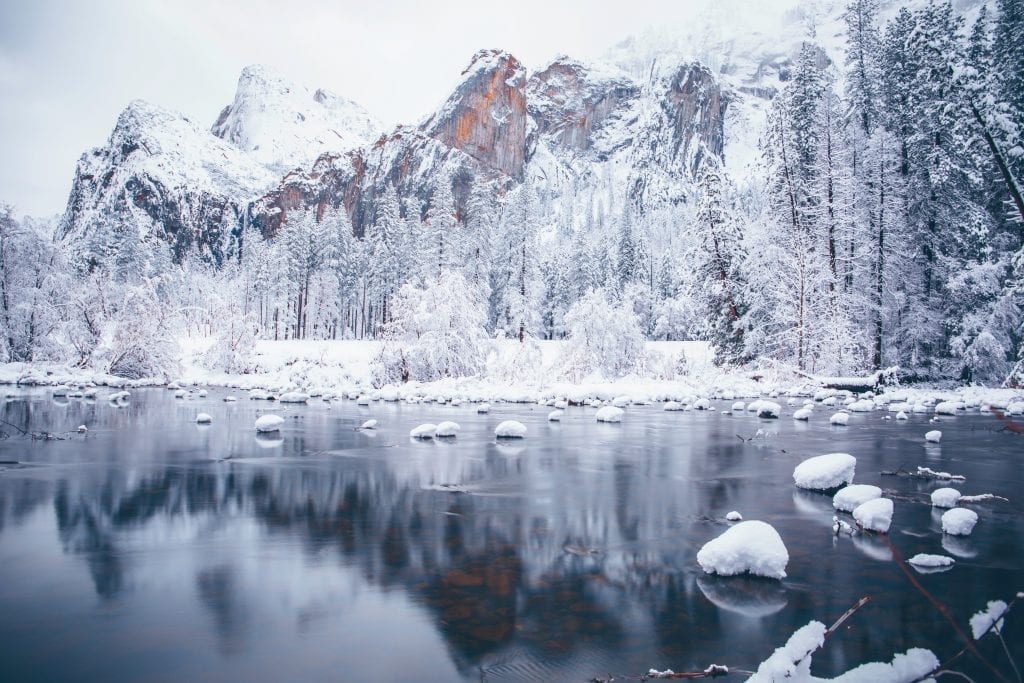 lake in yosemite national park in winter with snow covering the trees and ice on the lake