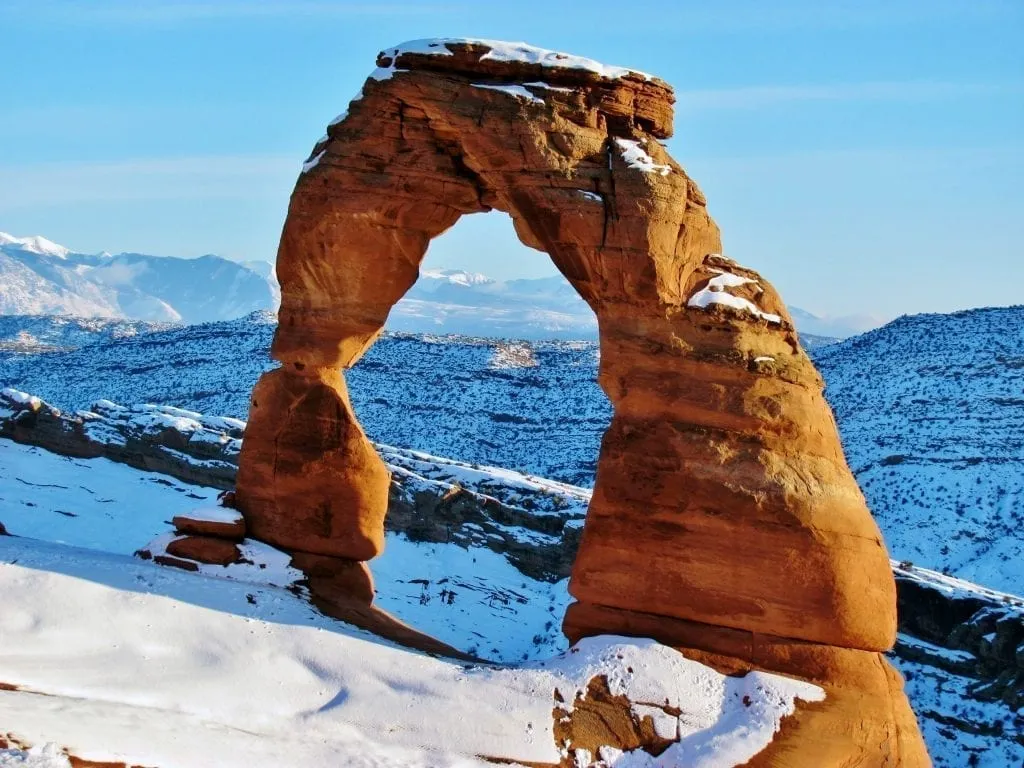 delicate arch in arches np with snow on the ground as seen when visiting the national park during winter