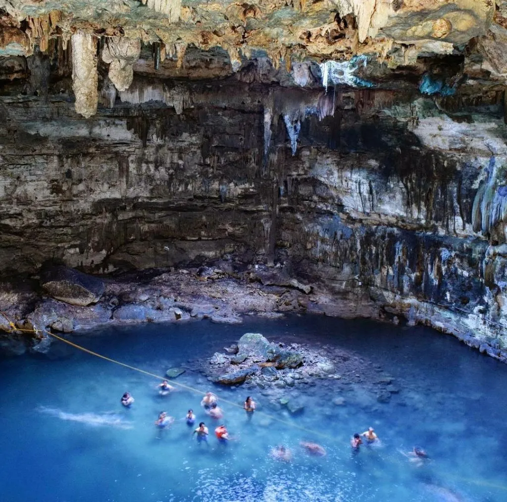 cenote samula as seen from above with a handful of swimmers enjoying the cenote