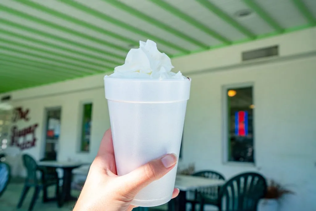 hand holding up an ice cream sundae in front of front porch at sugar shack tybee island restaurants